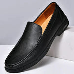 Men's black leather slip-on loafers with metal buckle and dark rubber sole