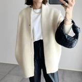 Cream cardigan with button placket, long sleeves, and relaxed drape over pants.