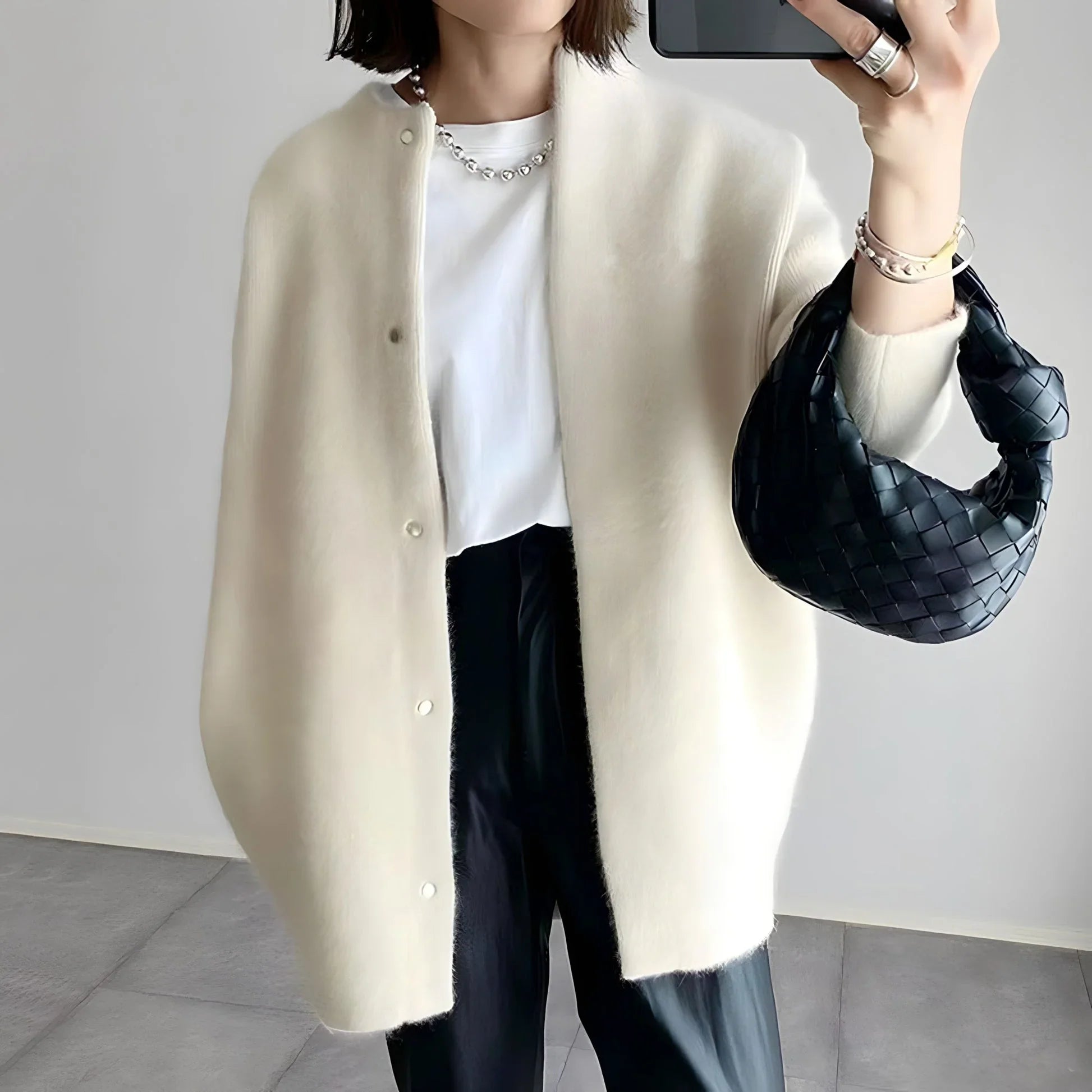 Cream cardigan with button placket, long sleeves, and relaxed drape over pants.