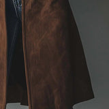 Brown suede trench coat hem and front placket over blue jeans, long straight cut.