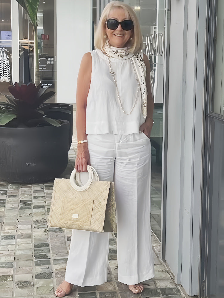 White sleeveless top and wide-leg pants with neck scarf and woven tote bag