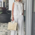 White sleeveless top and wide-leg pants with neck scarf and woven tote bag