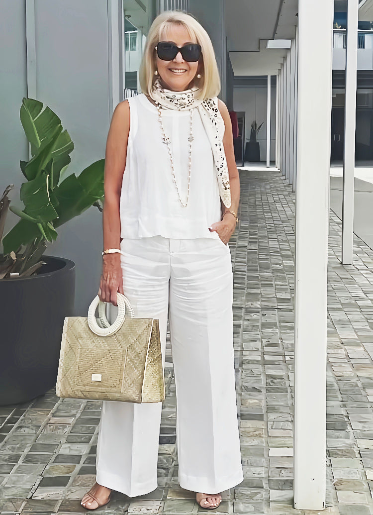 White sleeveless top and wide-leg pants with long beaded necklace