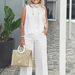 White sleeveless top and wide-leg pants with long beaded necklace