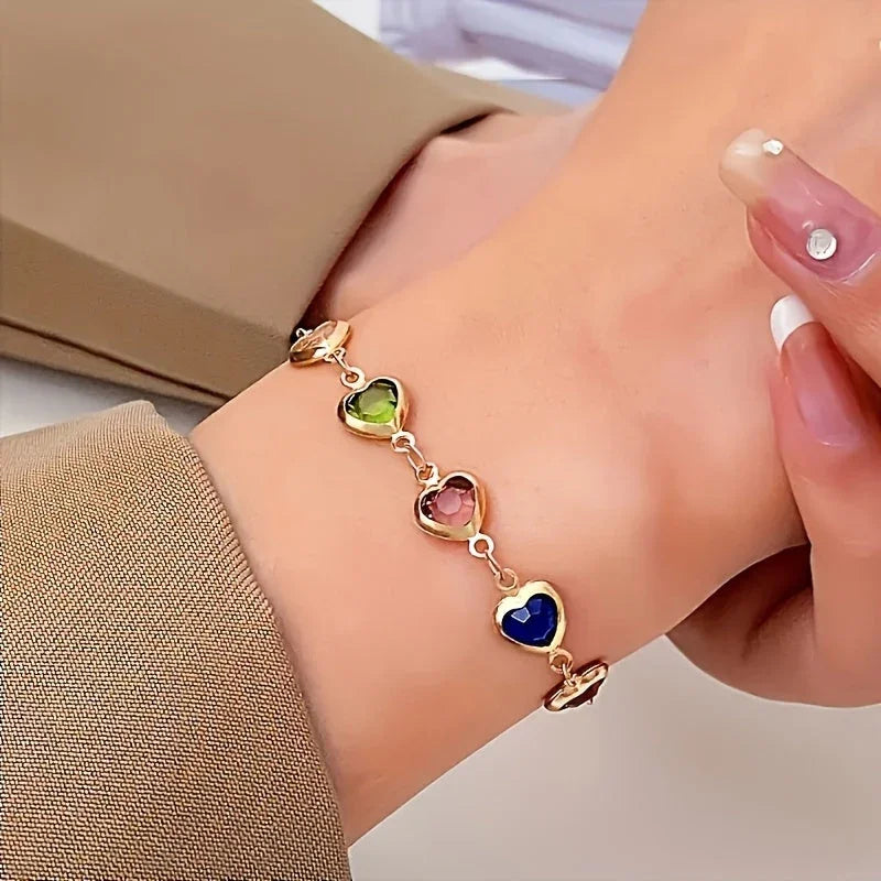 Heart charm bracelet with gold-tone chain and multicolor heart stones on wrist