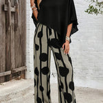 Black asymmetrical top with draped sleeves paired with wide-leg boho pants, black-on-cream dot print