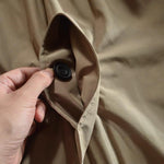 Close-up of beige jacket collar with black snap button