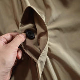 Close-up of beige jacket collar with black snap button