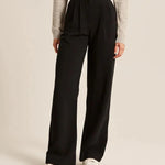 Black high-rise wide-leg pants with pleats and belt loop waist, side view