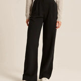 Black high-rise wide-leg pants with pleats and belt loop waist, side view