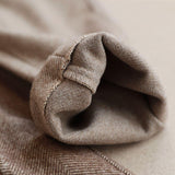 Beige herringbone trouser fabric close-up with stitched fold edge
