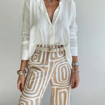 Two-piece outfit: light blouse with open V-neck and belt; cream patterned wide-leg pants