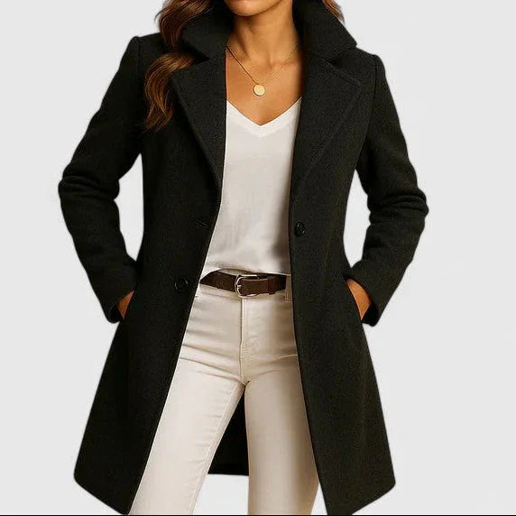 Black long coat with notched lapels and button front, worn over light-colored pants