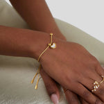 Gold heart charm bracelet on hand wrist with small heart bead pendant.