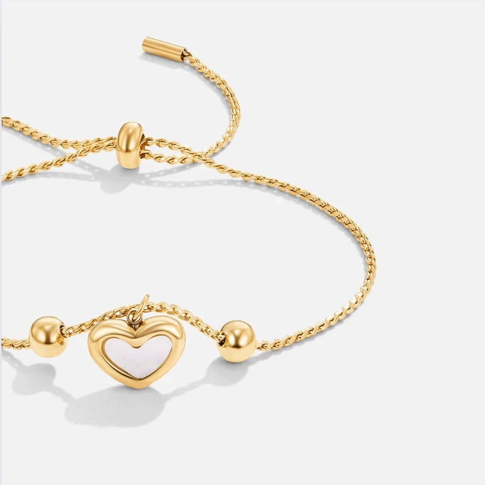Gold chain bracelet with heart charm and bead details, toggle closure.