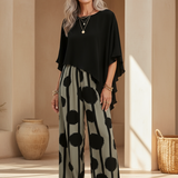 Black asymmetrical top with flutter sleeves and wide-leg boho pants in black-on-cream dot print