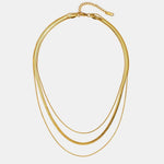 Gold multi-layer necklace featuring stacked oval chains with small bead toggle clasp
