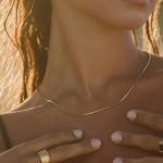 Gold snake choker necklace, close-up on neckline with thin chain detail