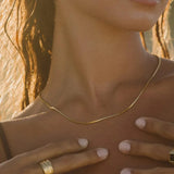 Gold snake choker necklace, close-up on neckline with thin chain detail