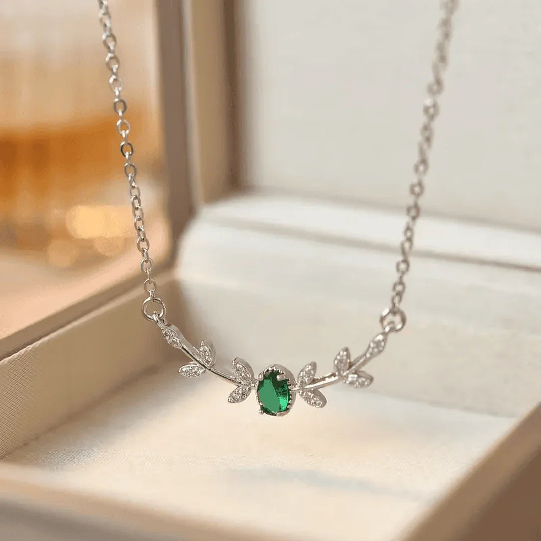 Silver-tone emerald pendant necklace with leaf charm and small stone accents