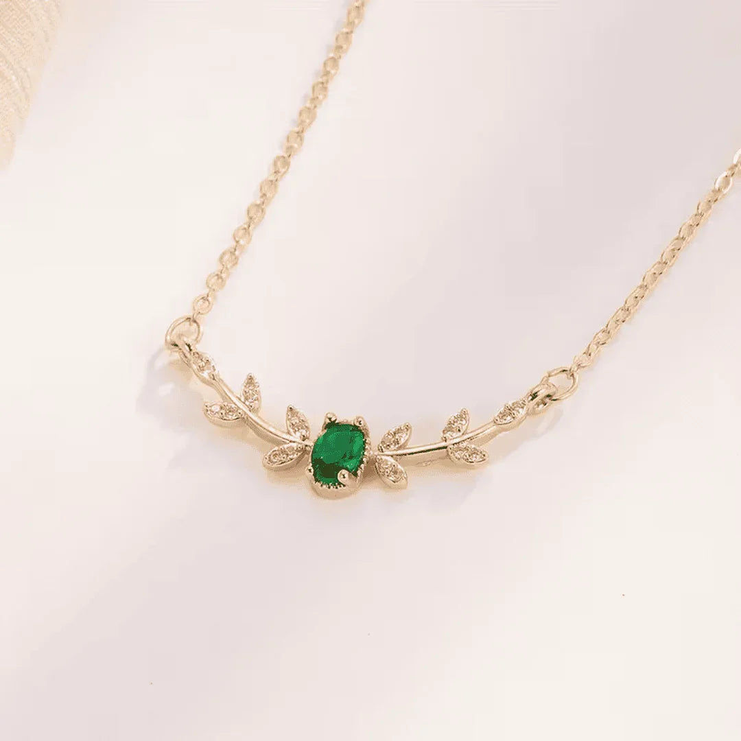 Gold-tone emerald pendant necklace with leaf and small stone accents