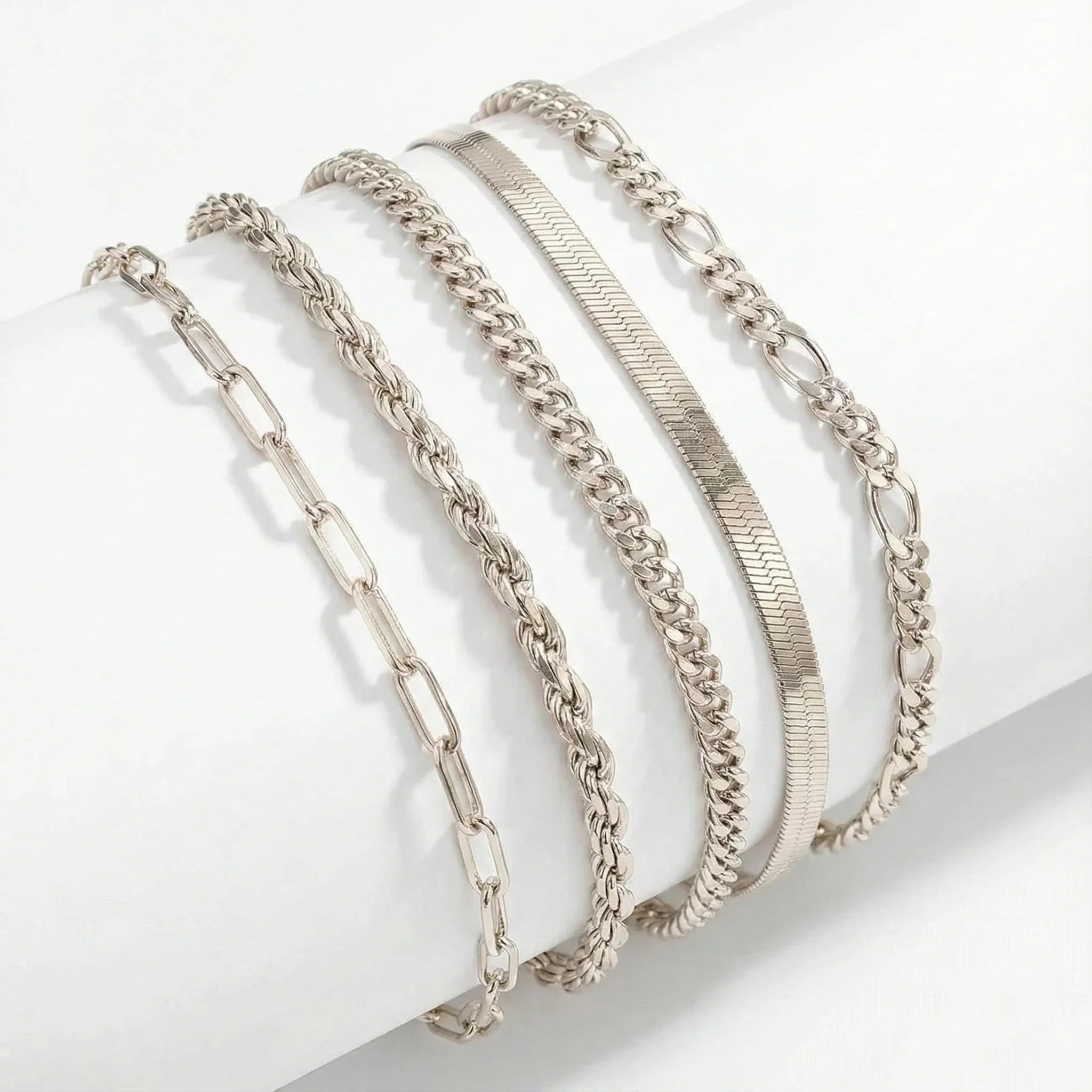 White gold bracelet set with mixed chain and curb links, layered bangles on display