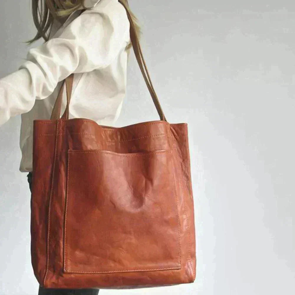 Rust orange leather tote bag held by model, open top with dual handles