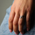 Silver band ring with dark inlay stripe, worn on finger