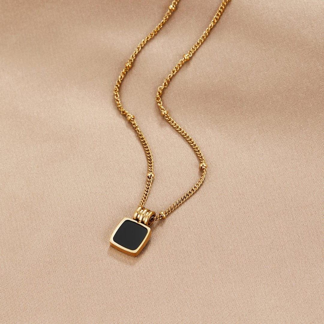 Gold pendant necklace with small black square charm on a fine chain