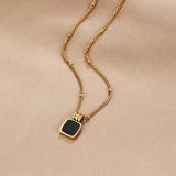 Gold pendant necklace with small black square charm on a fine chain