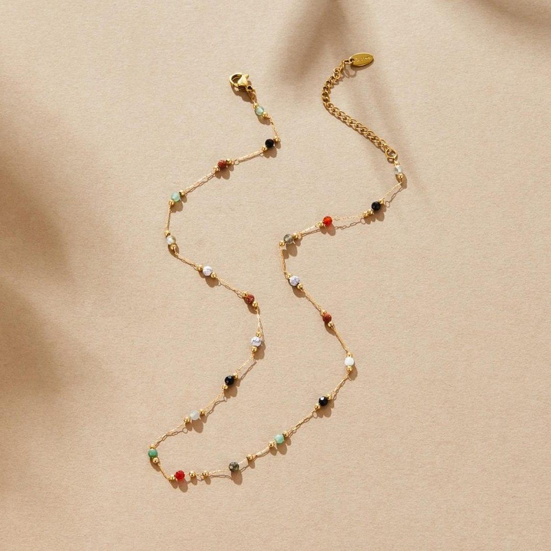 Gold beaded gem necklace with multicolor stones, clasp and chain visible