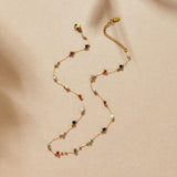 Gold beaded gem necklace with multicolor stones, clasp and chain visible