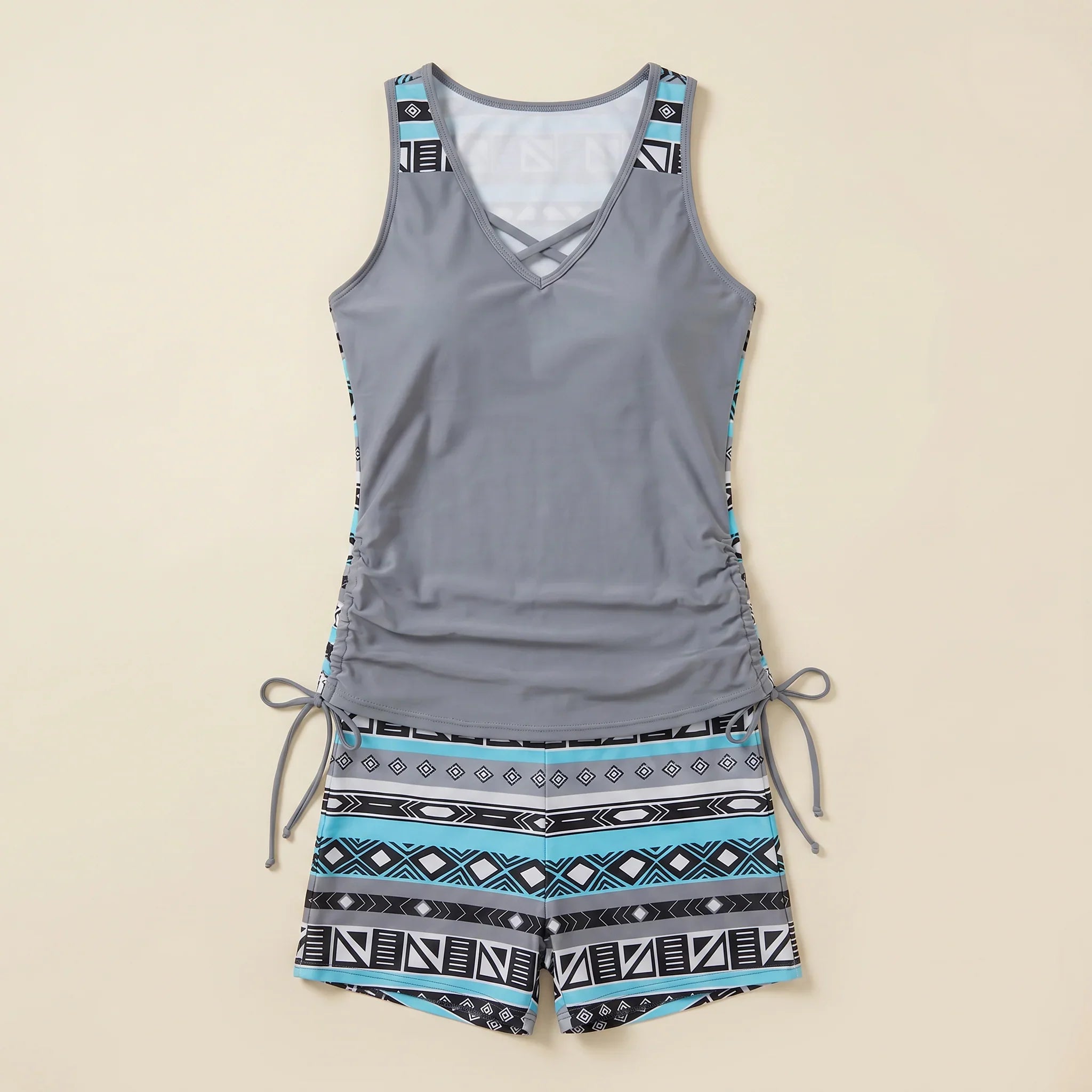 Gray tankini set with crisscross V-neck and teal geometric shorts with drawstring ties
