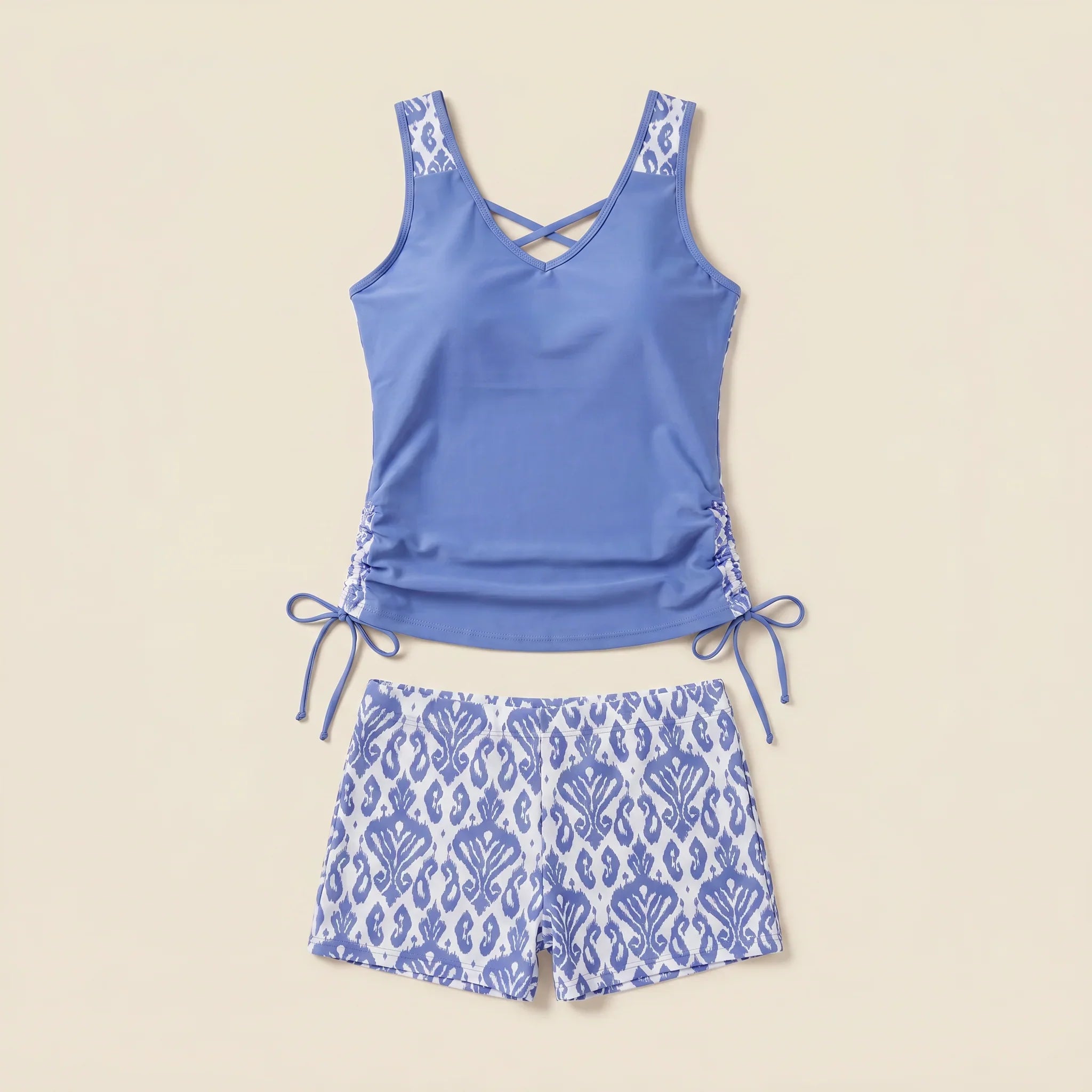Blue tankini set with crisscross V-neck, ruched sides, and patterned drawstring shorts