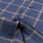 Navy checkered dress shirt placket close-up with dark buttons and tan plaid lines.