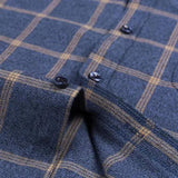 Navy checkered dress shirt placket close-up with dark buttons and tan plaid lines.