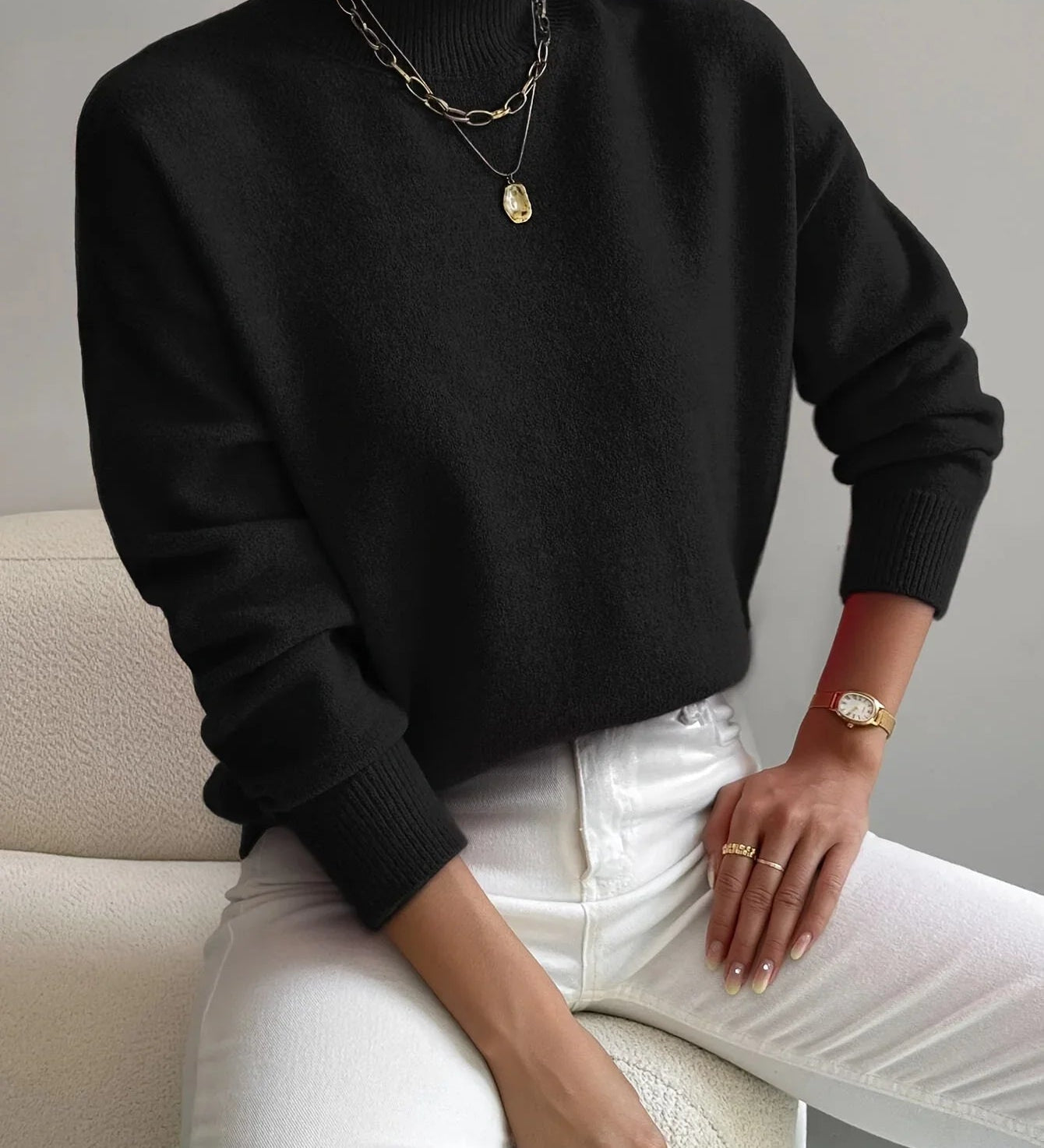 Black knit crewneck sweater with long sleeves and ribbed cuffs and hem