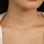 Gold pearl beaded necklace with small round white beads, worn close to neck