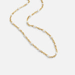 Gold-tone chain necklace with small white pearl beads, flat lay