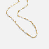 Gold-tone chain necklace with small white pearl beads, flat lay