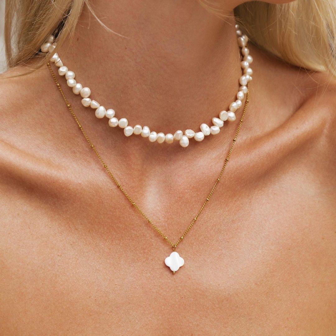 Gold pendant necklace with white pearl bead strand and clover charm