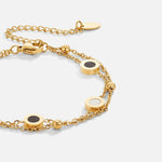 Gold chain bracelet with black and white circular charms and front clasp detail
