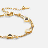 Gold chain bracelet with black and white circular charms and front clasp detail
