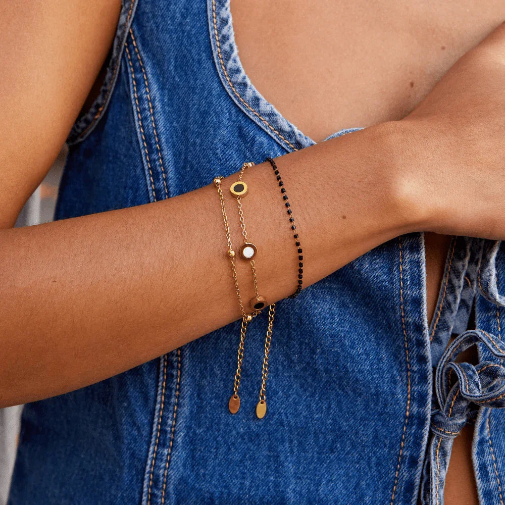 Gold chain bracelet with round black-and-white stone charms and dangling drops