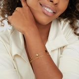 Gold chain bracelet with small black-and-white round stone charms on wrist