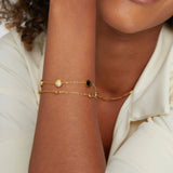 Gold chain bracelet featuring a black and white round stone center charm
