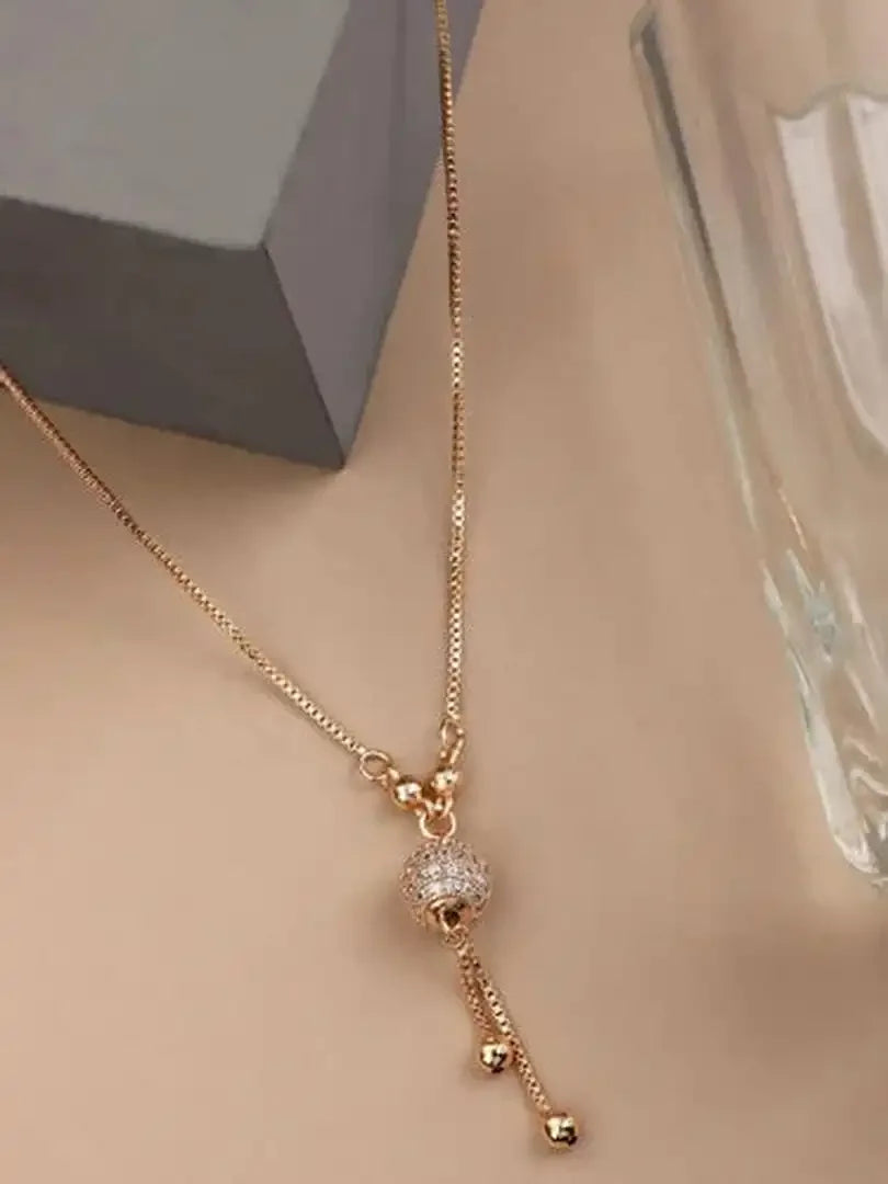Gold long chain pendant necklace with round crystal-like centerpiece and tassel drops