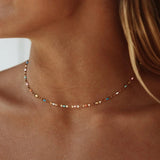 Gold-tone delicate choker necklace with small multicolor stones along the chain
