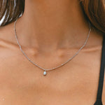 Silver opal pendant necklace with small round opal charm on a delicate chain