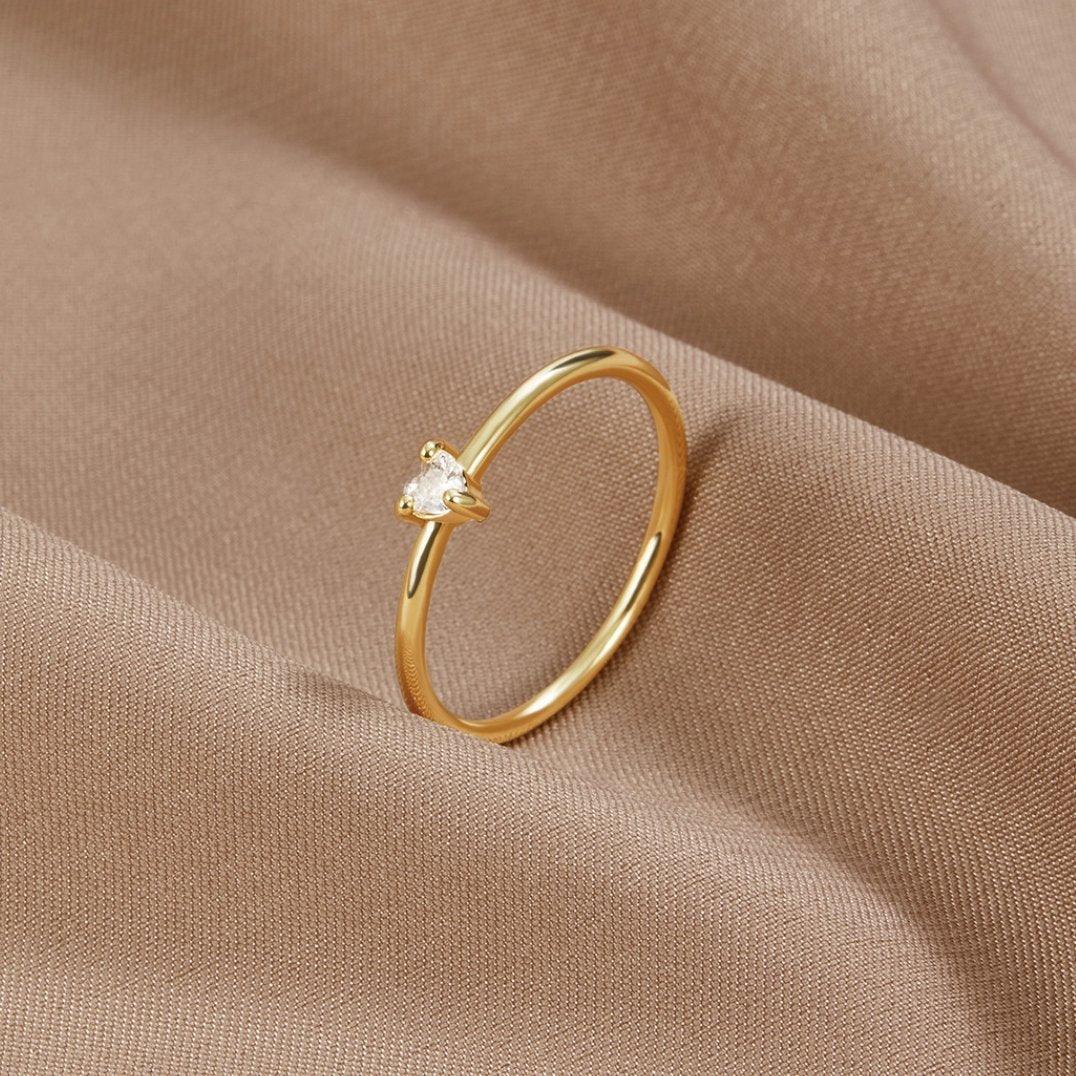 Gold ring with smooth band and small clear stone set on side view